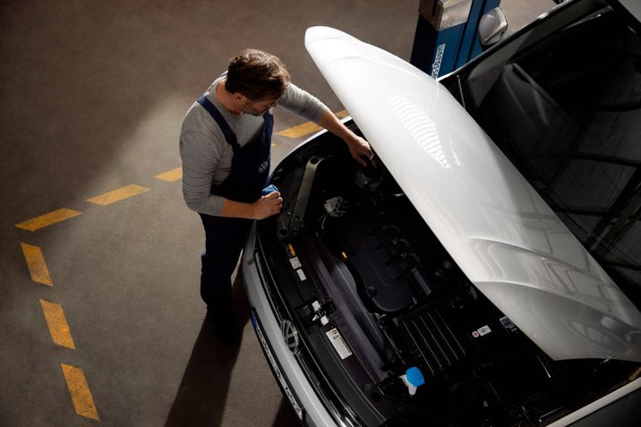 Mit den Vorteilspaketen für alle Modelle älter als 4 Jahre der Marken ✓ VW ✓ Audi ✓ SEAT ✓ Skoda ✓ CUPRA halten Sie ihr Fahrzeug mobil. - Mechaniker welcher in Motorraum reinschaut
